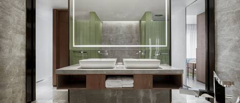 A modern bathroom with a large mirror, two sinks, a bathtub, and a wooden vanity.