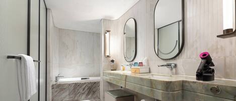 A modern bathroom with a marble vanity, a bathtub, and a large mirror.