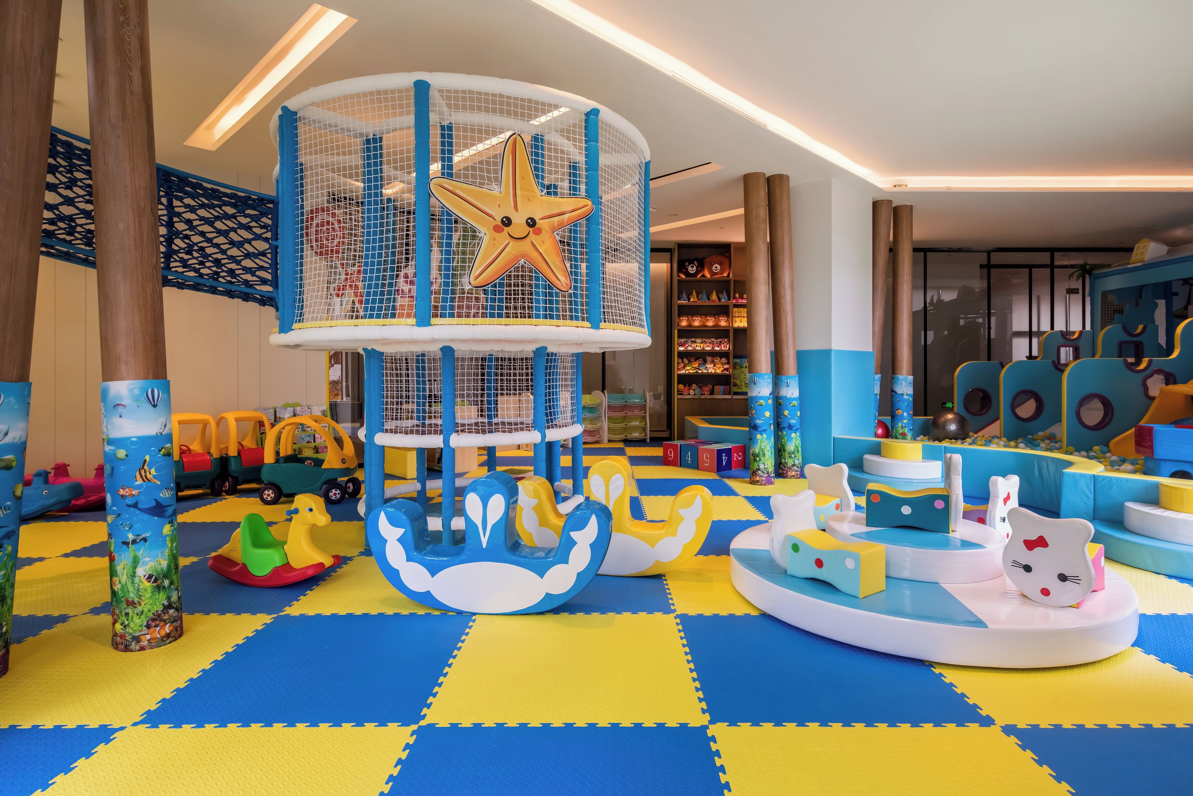 A children's play area with a climbing structure, soft play mats, and various toys.