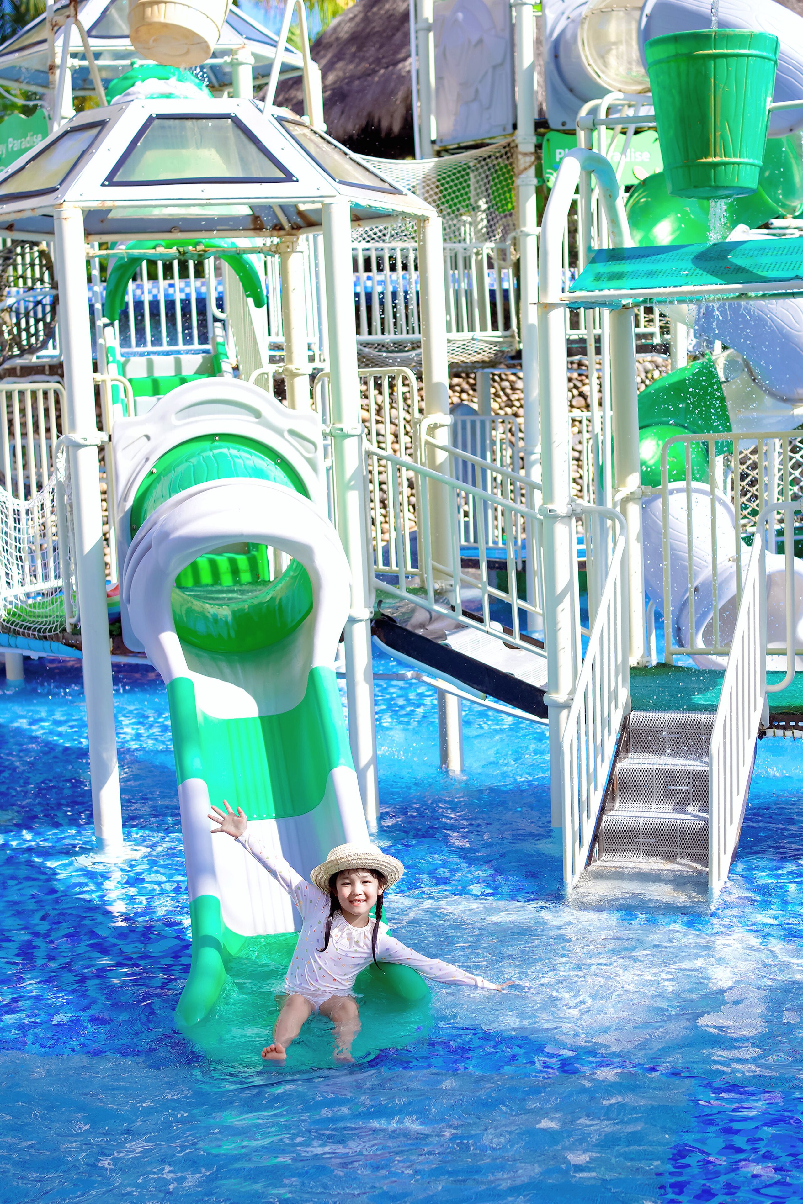Un parc aquatique avec un toboggan aquatique aux couleurs verte et blanche et une piscine.
