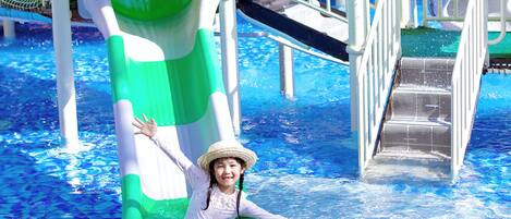 Un parque acuático con un tobogán de agua verde y blanco y una piscina.