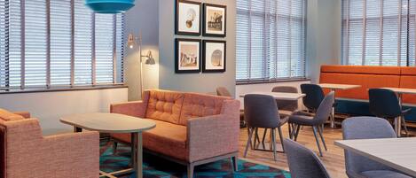A modern lounge area with seating arrangements, a patterned carpet, and framed pictures on the wall.