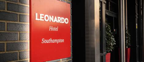 A red sign with the name 'LEONARDO Hotel' and the location 'Southampton' on a brick wall.