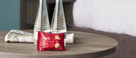 A round wooden table with two glass bottles and a packet of Bronte biscuits.