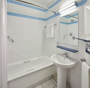 A bathroom with a bathtub, a sink, a mirror, and a shower area.