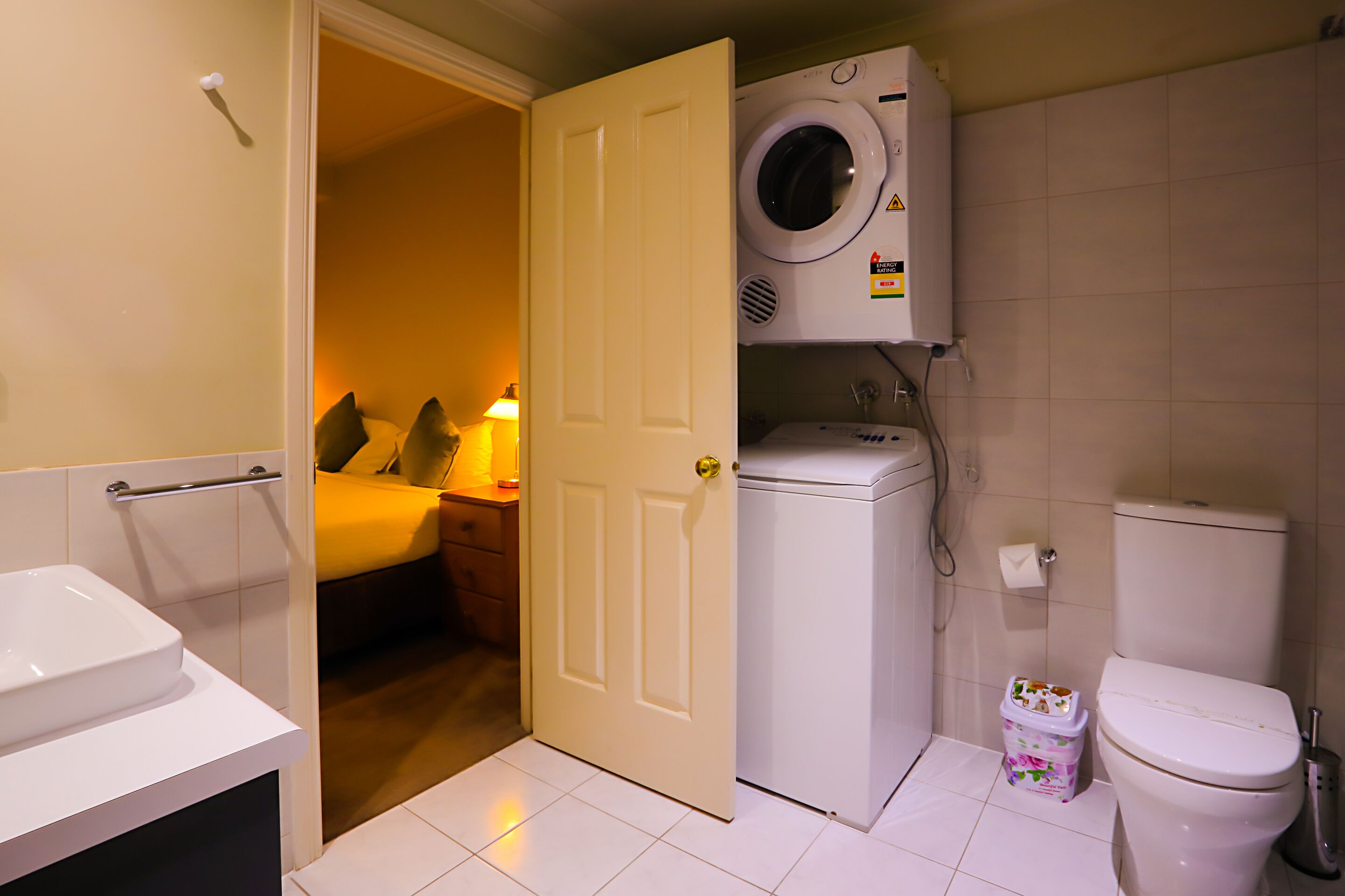 A compact bathroom with a washing machine, toilet, and a small sink.