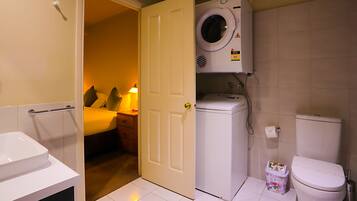 A compact bathroom with a washing machine, toilet, and a small sink.