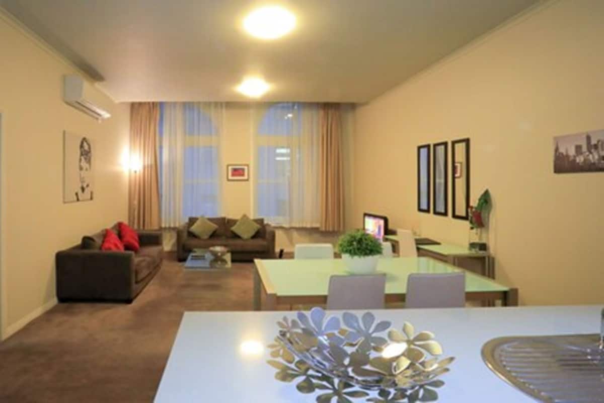 A modern living room with a sofa, a dining table with chairs, and a decorative centerpiece.