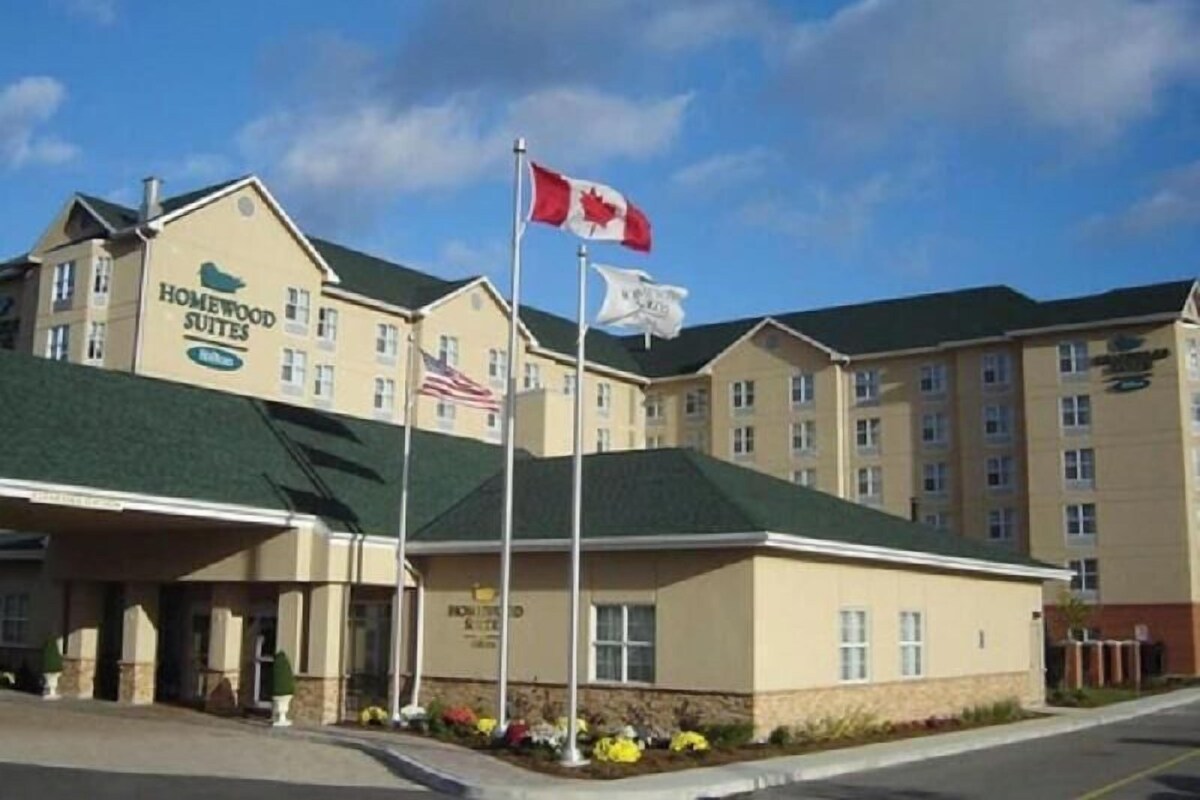 A hotel with a 'Homewood Suites' sign, a Canadian flag, and an American flag.