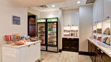 A kitchen with white cabinets, a marble countertop, and two beverage dispensers.