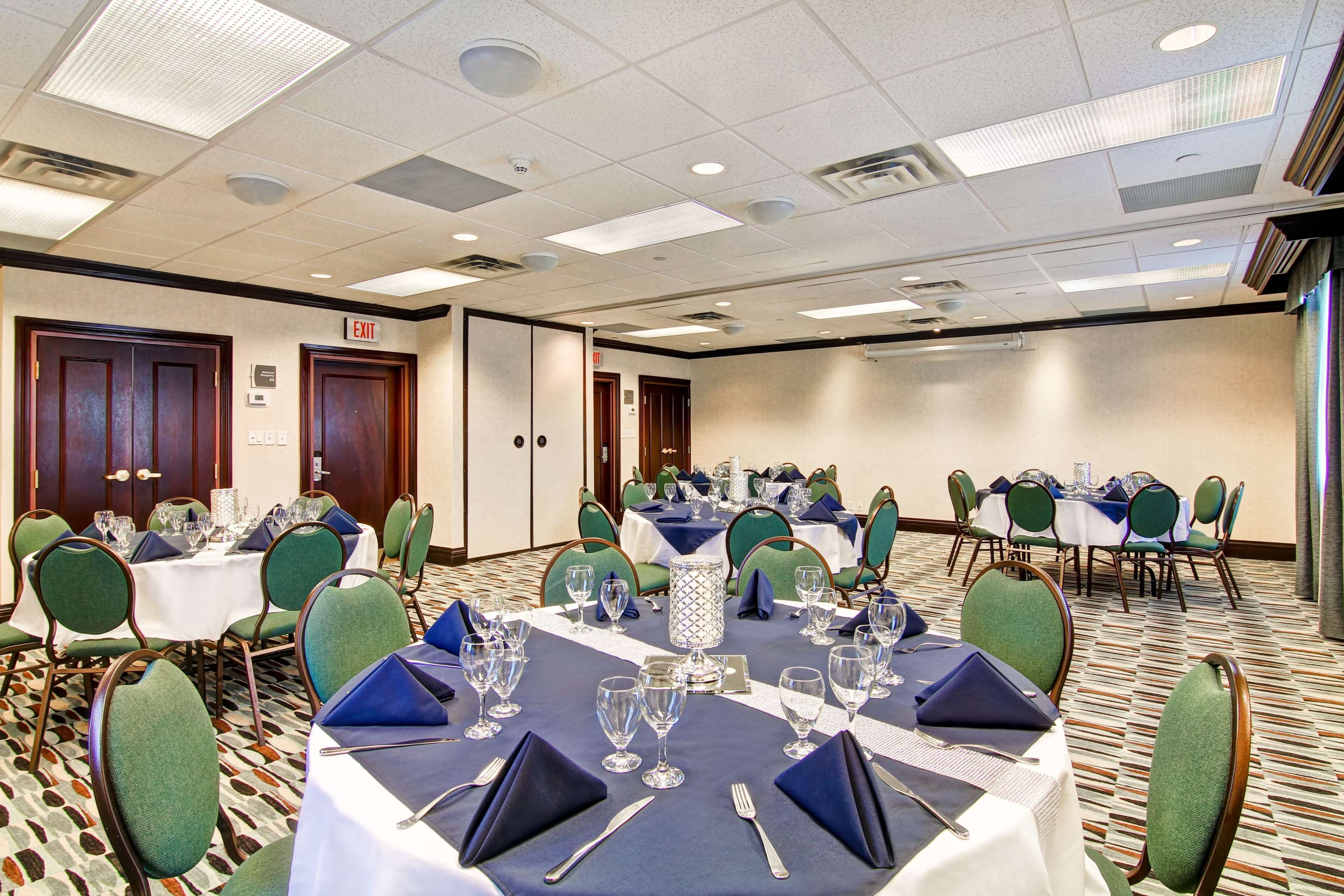 A conference room with multiple tables set for dining, equipped with chairs, tables, and glassware.
