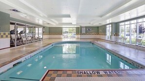 Une piscine intérieure dotée d’une zone à faible profondeur, de chaises longues et d’une vue sur l’extérieur.