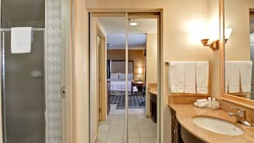 A hotel bathroom with a large mirror, a sink, and a shower.