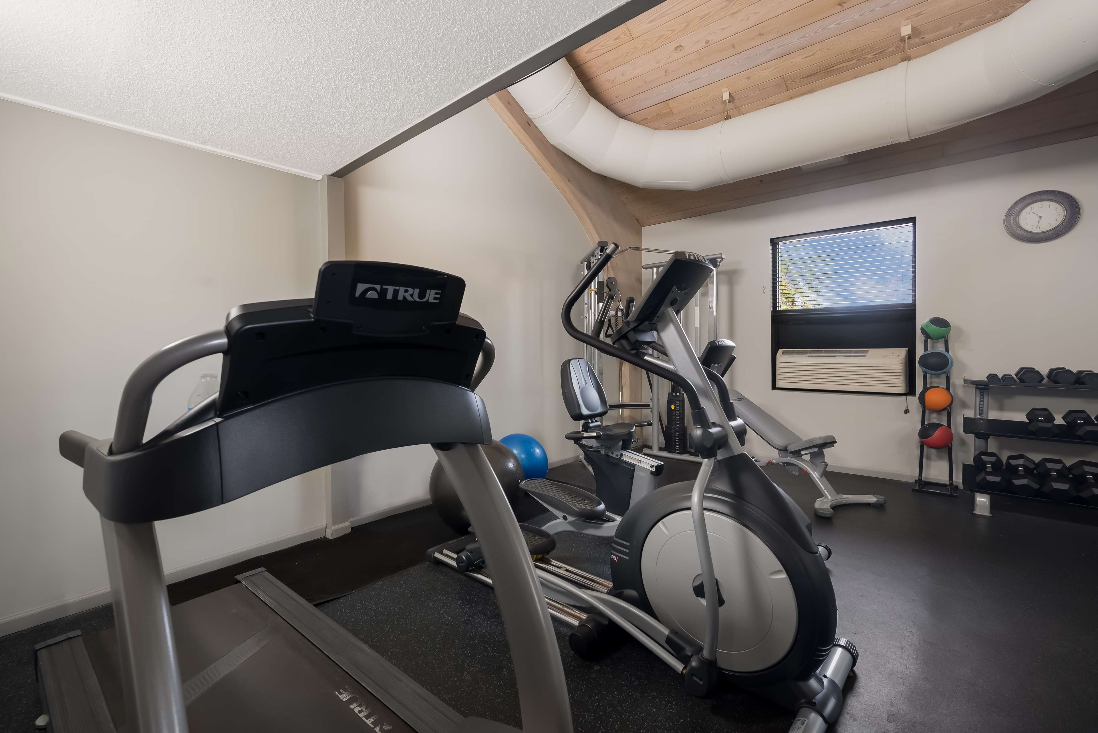 Un gimnasio con cinta de correr, elíptica y pesas.