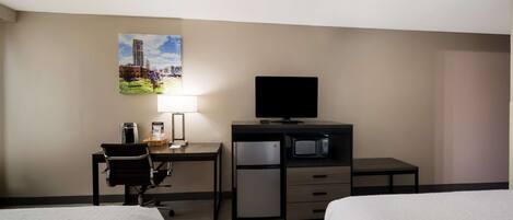 A hotel room with two beds, a desk with a chair, a television, a refrigerator, and a microwave.