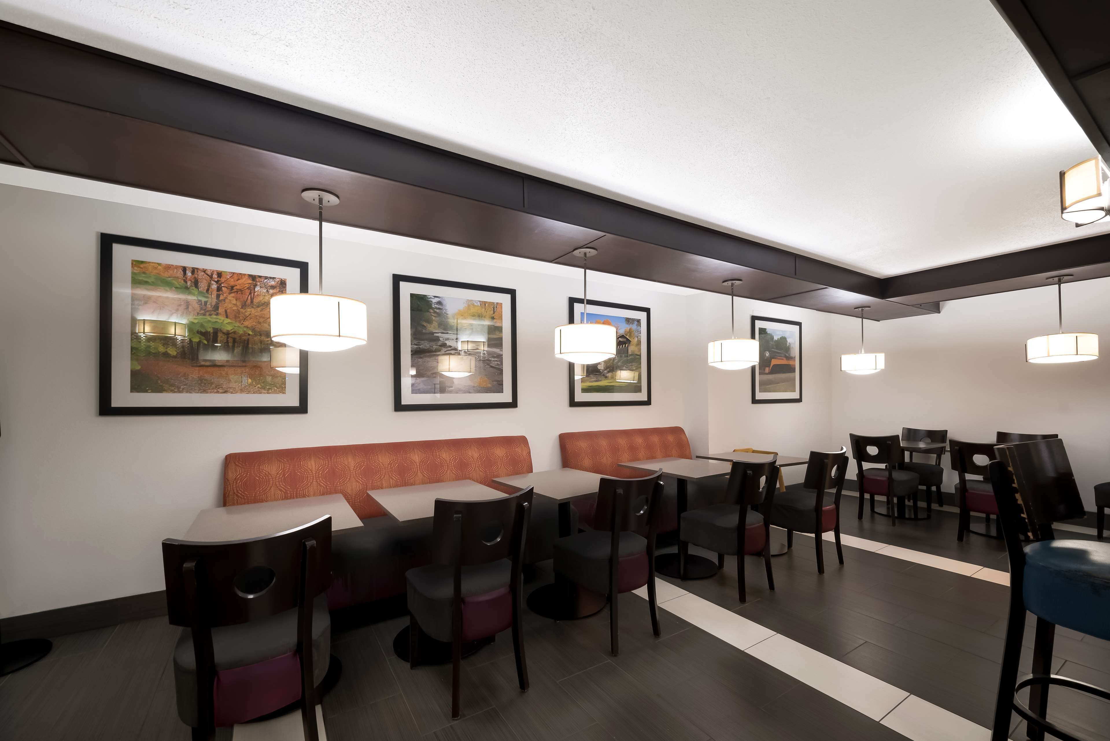 A modern restaurant with booths, tables, and hanging pendant lights.