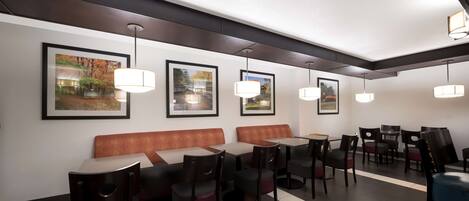 A modern restaurant with booths, tables, and hanging pendant lights.