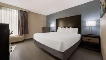 Una habitación de hotel con una cama grande, dos mesitas de noche con lámparas, un televisor y una ventana con cortinas.