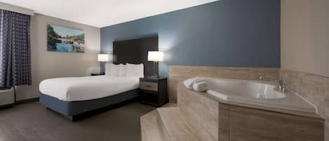 A modern hotel room with a large bed, a separate bathroom with a bathtub, and a painting on the wall.