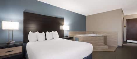 Een moderne hotelkamer met een groot bed, twee nachtkastjes met lampen, een ingebouwd bad en een hoofdbord van donker hout.