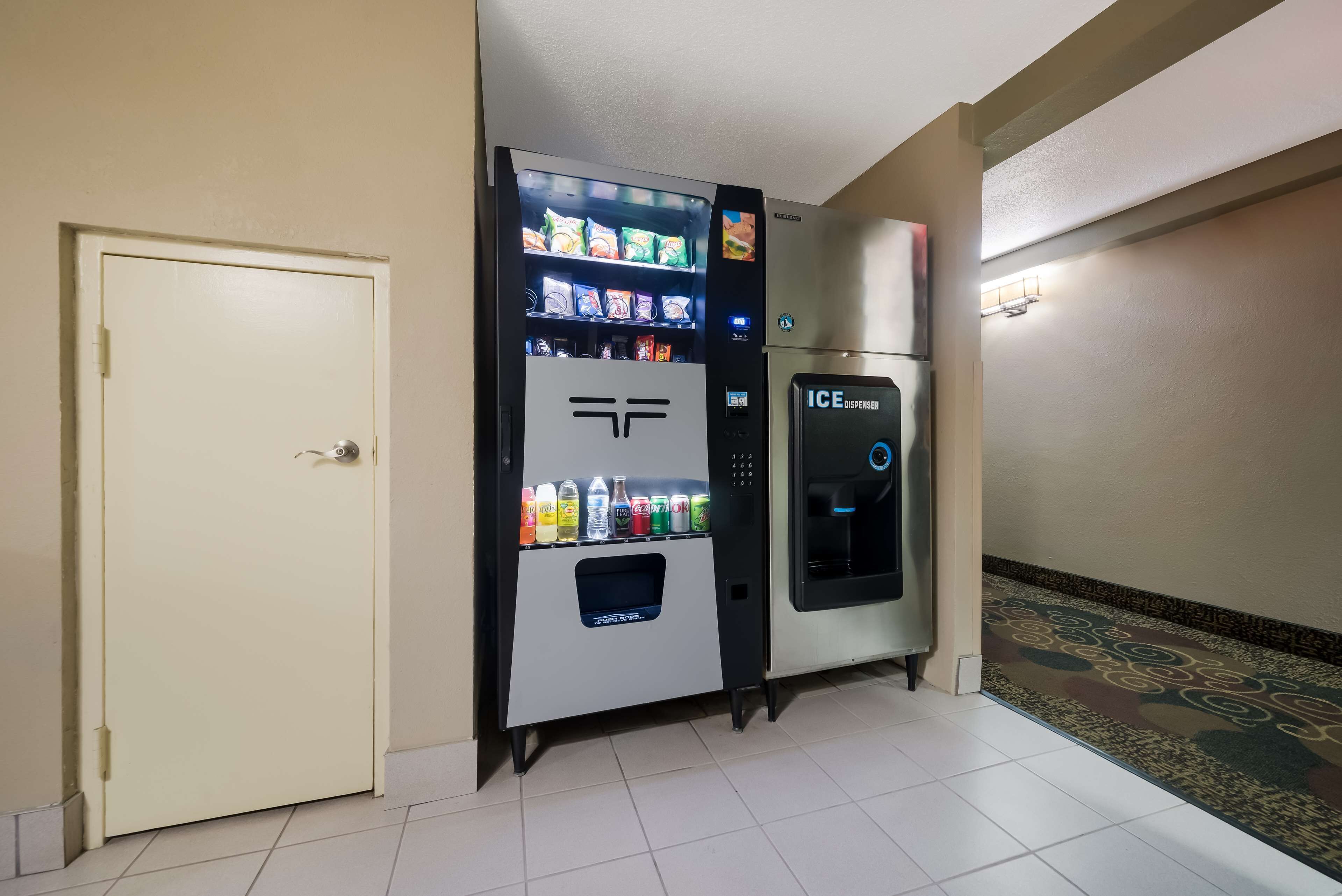 Een automaat met verschillende drankjes en snacks, een deur en een ijsdispenser.