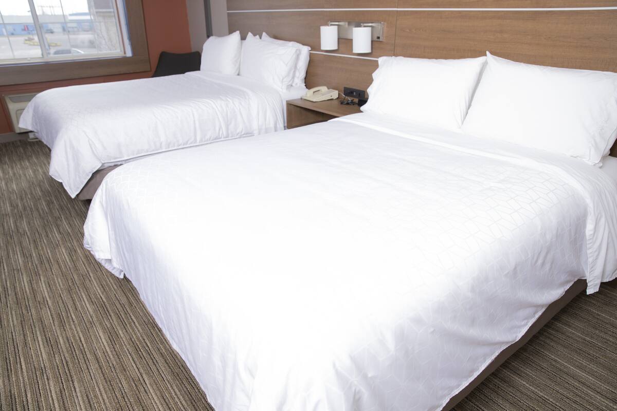 A hotel room with two beds, a nightstand with a phone, and a window with a view.