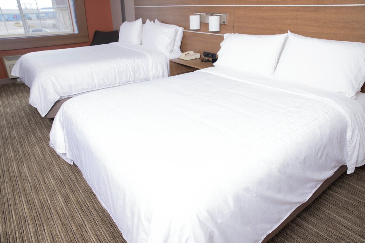 A hotel room with two beds, a nightstand, and a window.