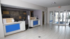 A reception area with two counters, a modern design with blue accents, and a tiled floor. - Holiday Inn Express Toledo West - Napoleon by IHG (Napoleon)