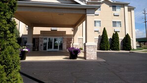 A hotel entrance with a covered entryway, brick facade, and potted plants. - Holiday Inn Express Toledo West - Napoleon by IHG (Napoleon)