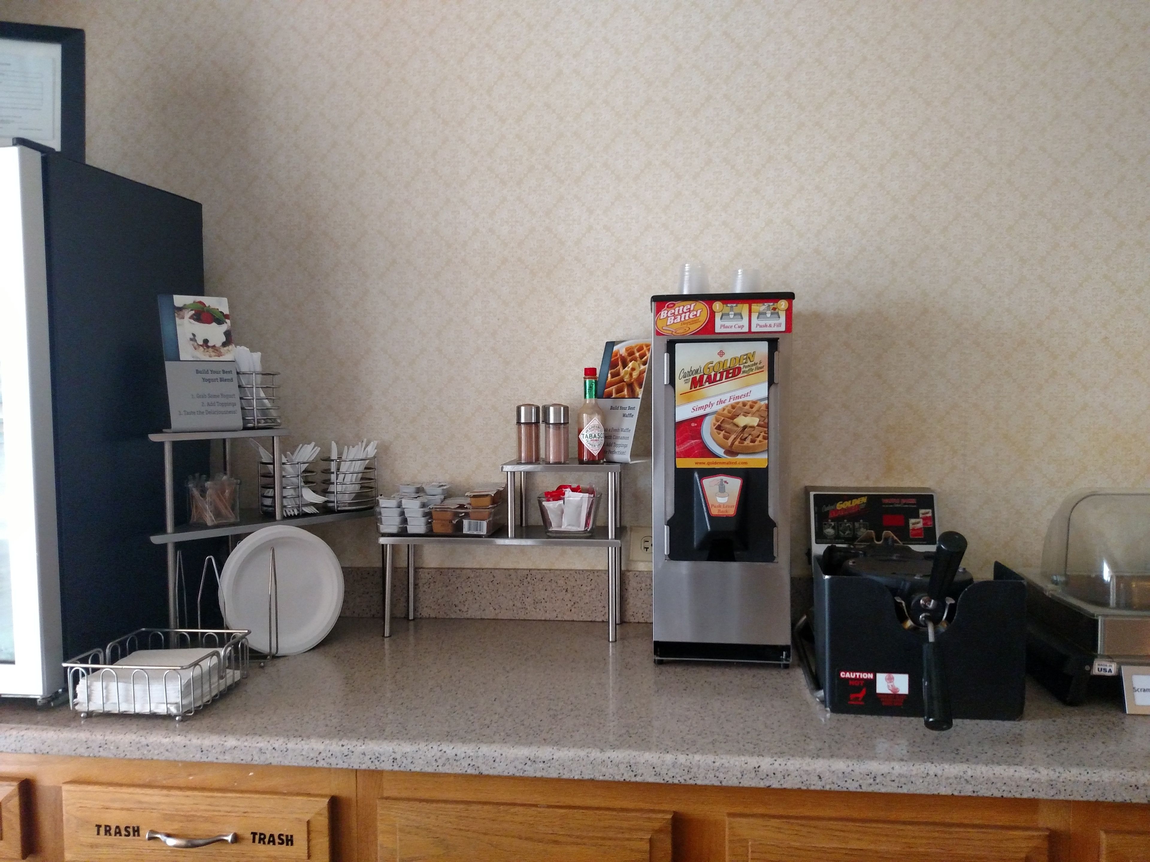 A kitchenette with a coffee machine, a waffle maker, and a coffee dispenser.