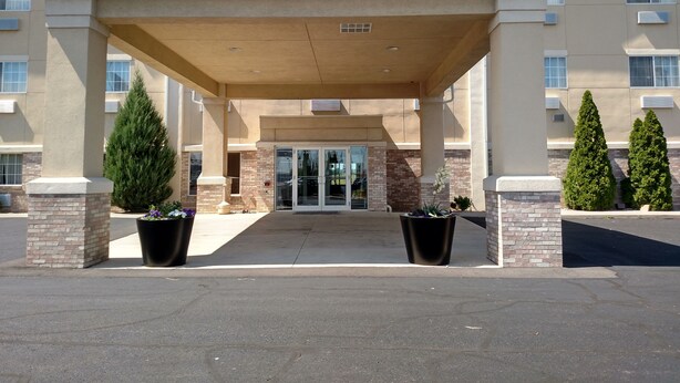 A hotel entrance with a covered walkway, brick pillars, and potted plants. - Holiday Inn Express Toledo West - Napoleon by IHG (Napoleon)