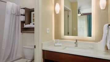 A bathroom with a toilet, a sink with a mirror, and a shower curtain.