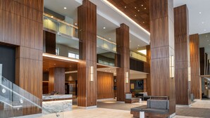A spacious lobby with high wooden columns, a marble reception desk, and a staircase. - Hilton Vancouver Washington (Vancouver)