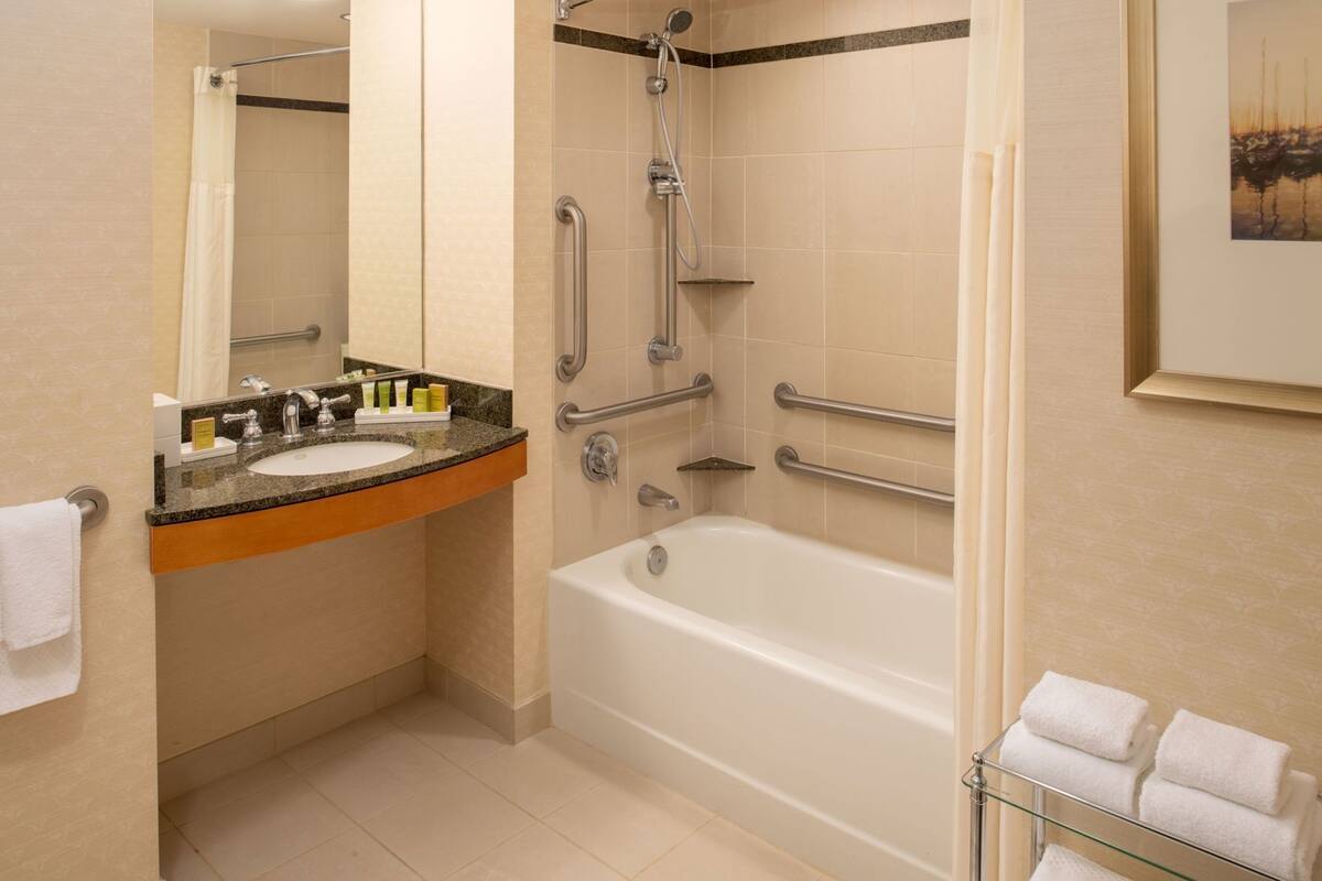 A bathroom with a sink, mirror, shower, and bathtub.