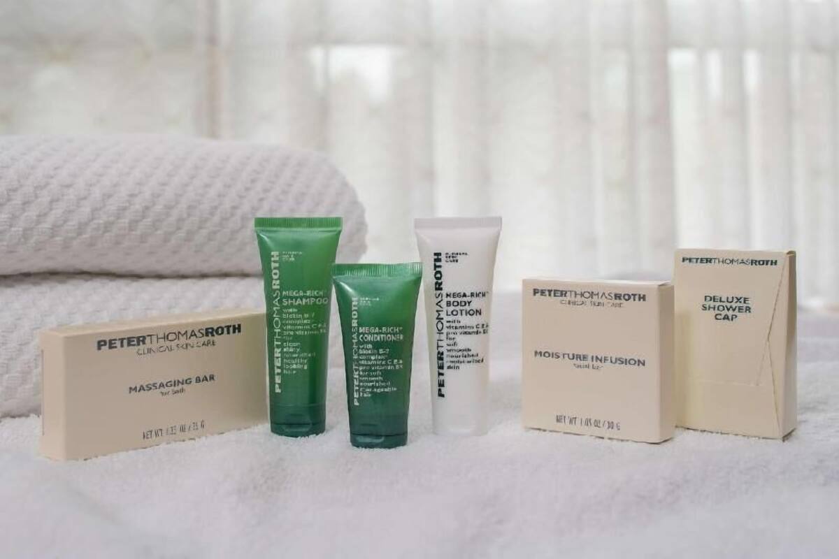 A set of Peter Thomas Roth skincare products including a massage bar, shampoo, conditioner, lotion, and a shower cap.