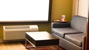 A modern living room with a flat-screen TV, a sofa, a coffee table, and a floor lamp. - Holiday Inn Express & Suites Maryville by IHG (Maryville)