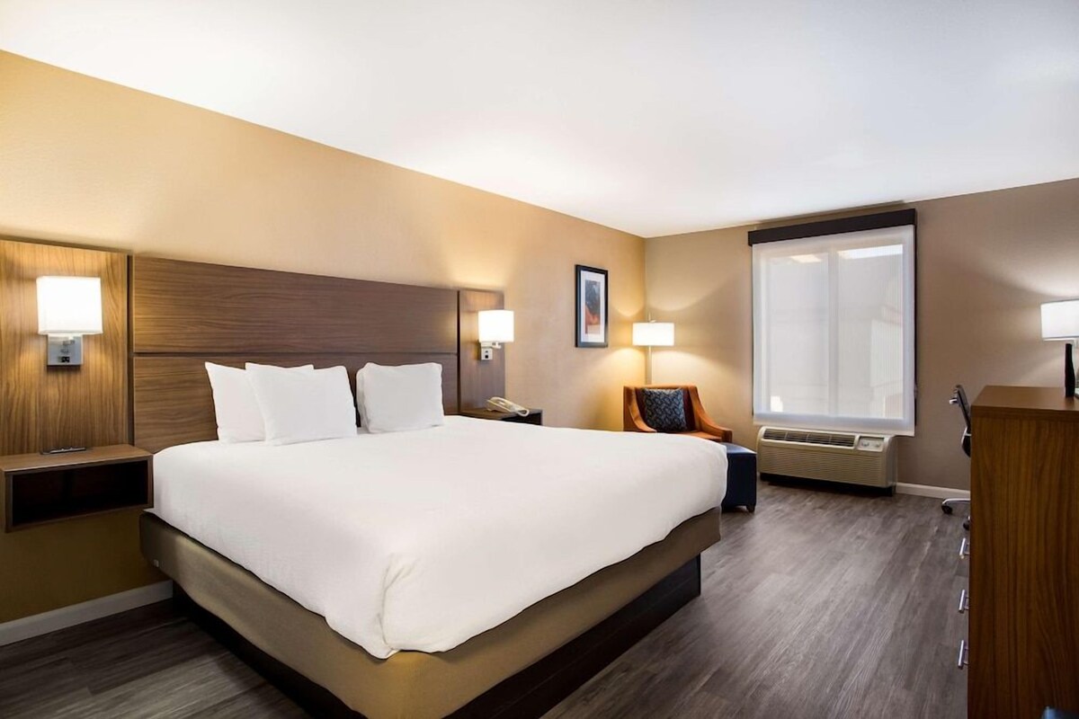 A hotel room with a large bed, bedside lamps, a desk, and a window.
