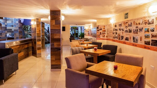 Un moderno vestíbulo de hotel con mostrador de recepción, zona de estar y una pared mostrando fotografías históricas.