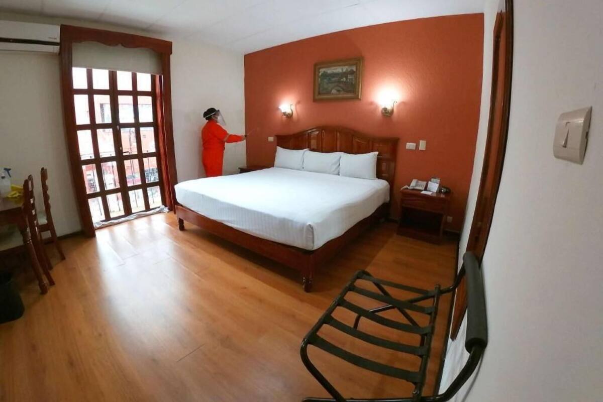 Un dormitorio con cama de madera, mesita de noche, silla y ventana con vistas.