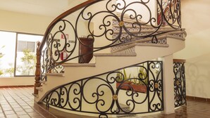 Una escalera curva con barandillas de metal negro decorativas y una pared color crema.