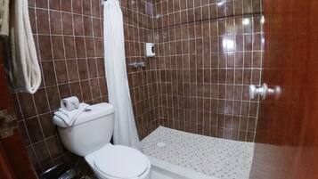 A bathroom with a toilet, shower, and a tiled floor.