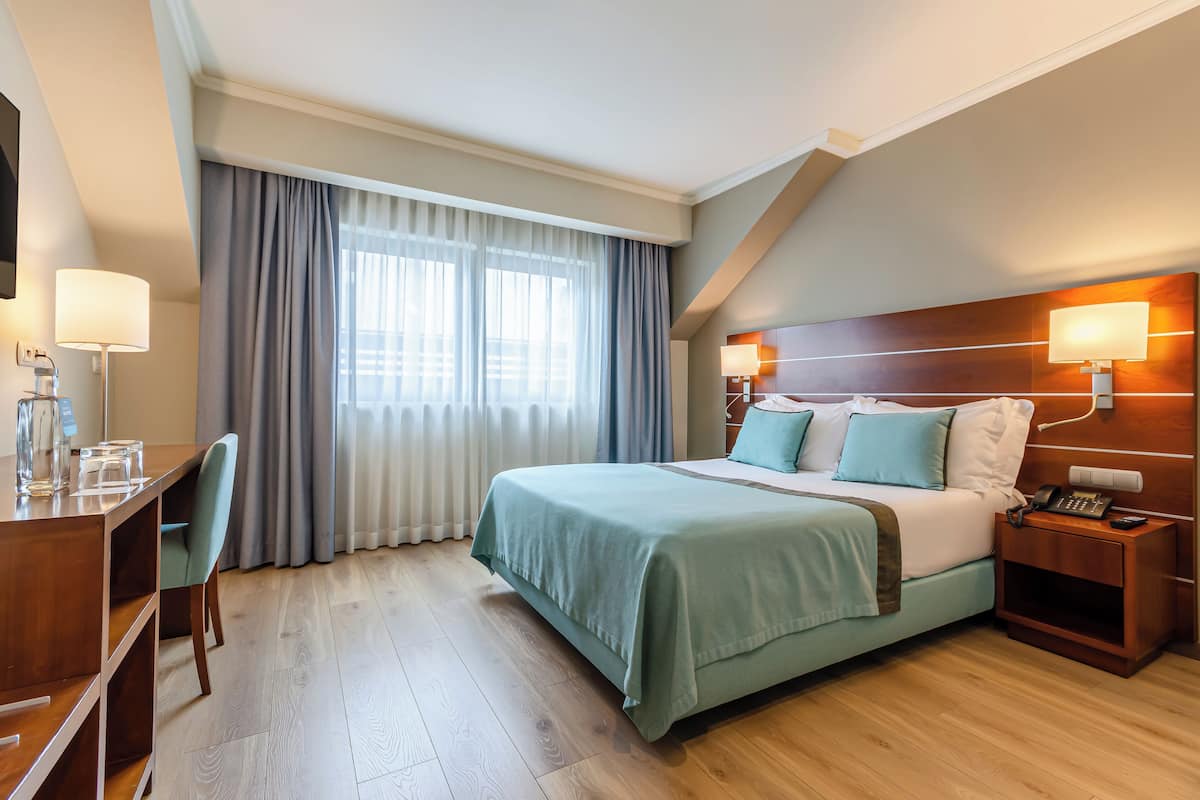 Una habitación de hotel con cama, mesitas de noche, escritorio y una silla.