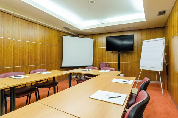 Une salle de conférence aux murs lambrés, dotée d’une grande table et de nombreuses chaises.