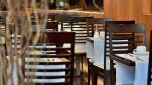 Un interior de restaurante con sillas de madera, manteles blancos y un diseño moderno.