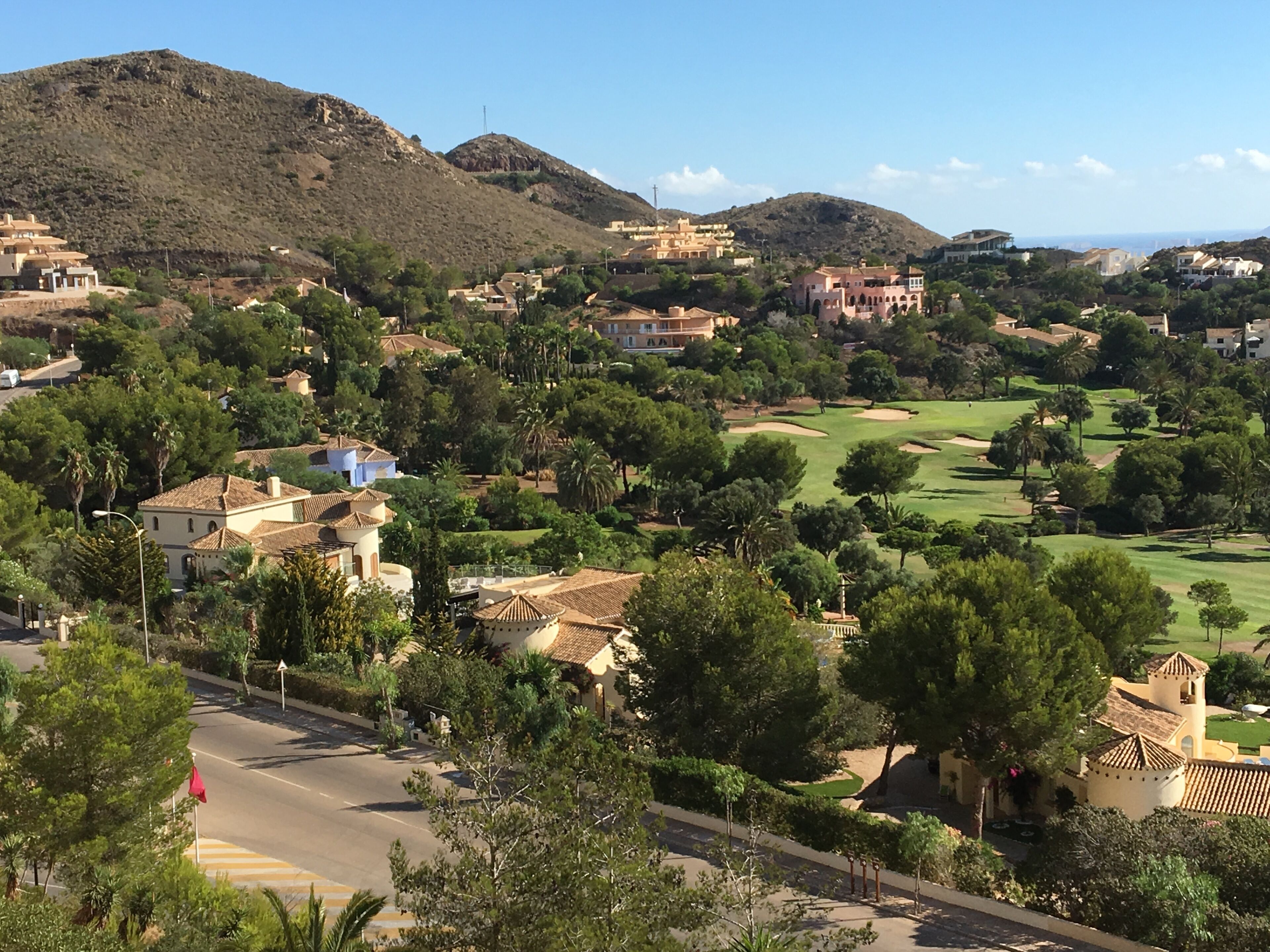 A residential area with houses, a golf course, and a mountain in the background.