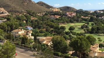 A residential area with houses, a golf course, and a mountain in the background.