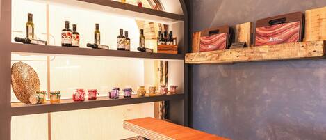 Zona de bar con estantes mostrando botellas y frascos, mostrador de madera y pared rústica con paneles de madera.