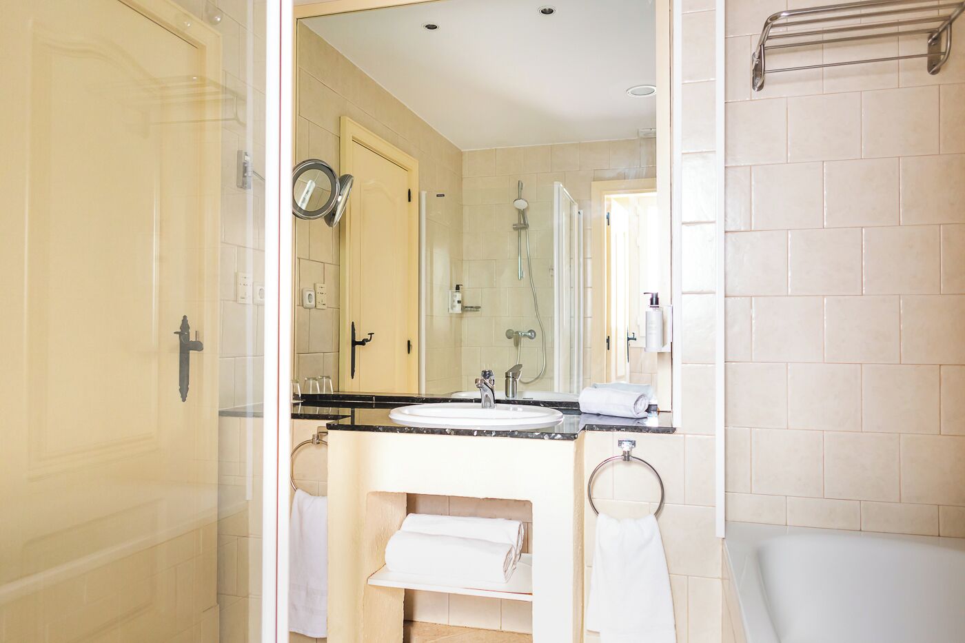 A modern bathroom with a glass shower enclosure, a white sink, and a large mirror.