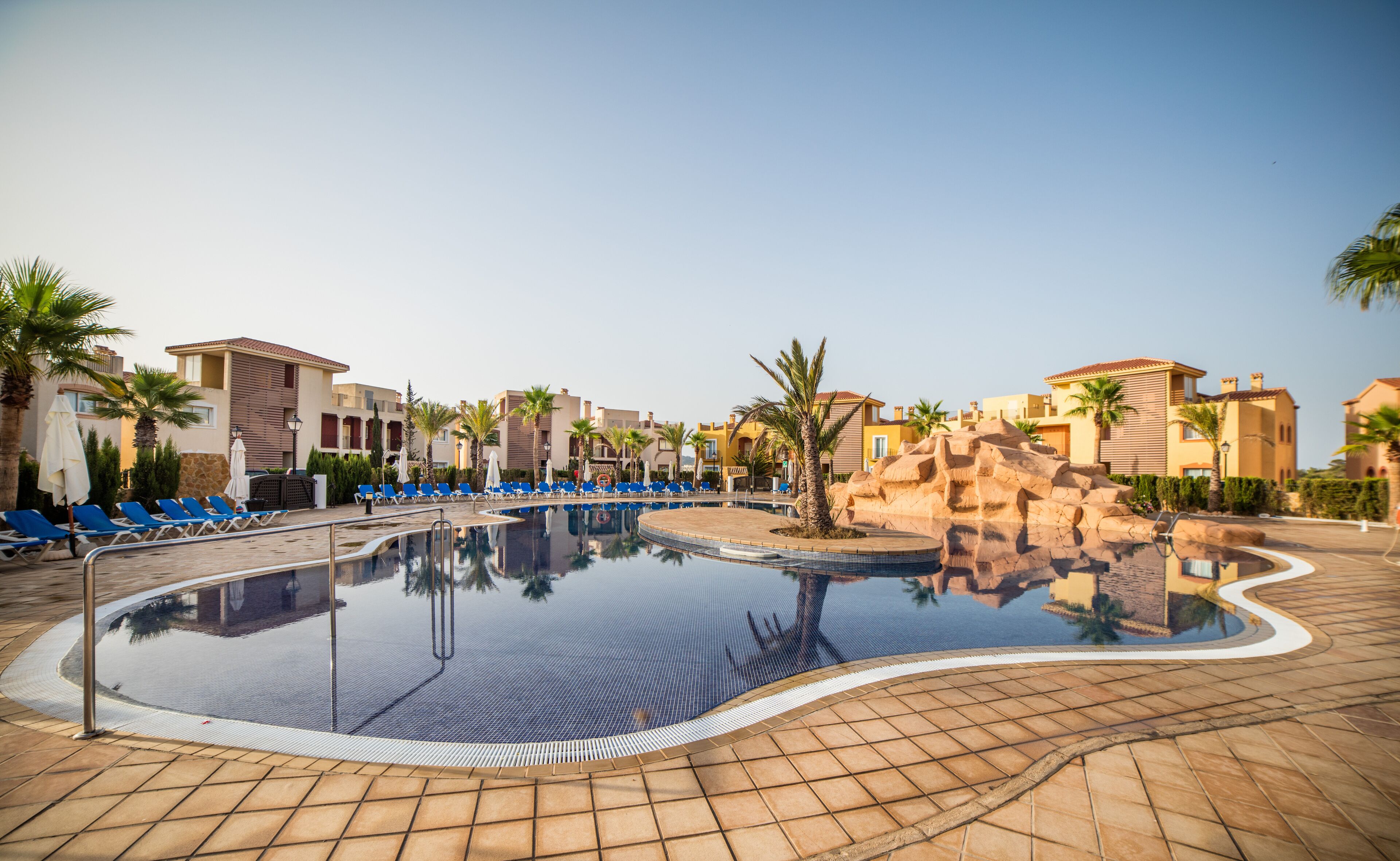 A resort pool area with lounge chairs and palm trees.