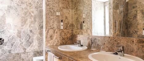 A modern bathroom with two sinks, a shower, and a toilet.